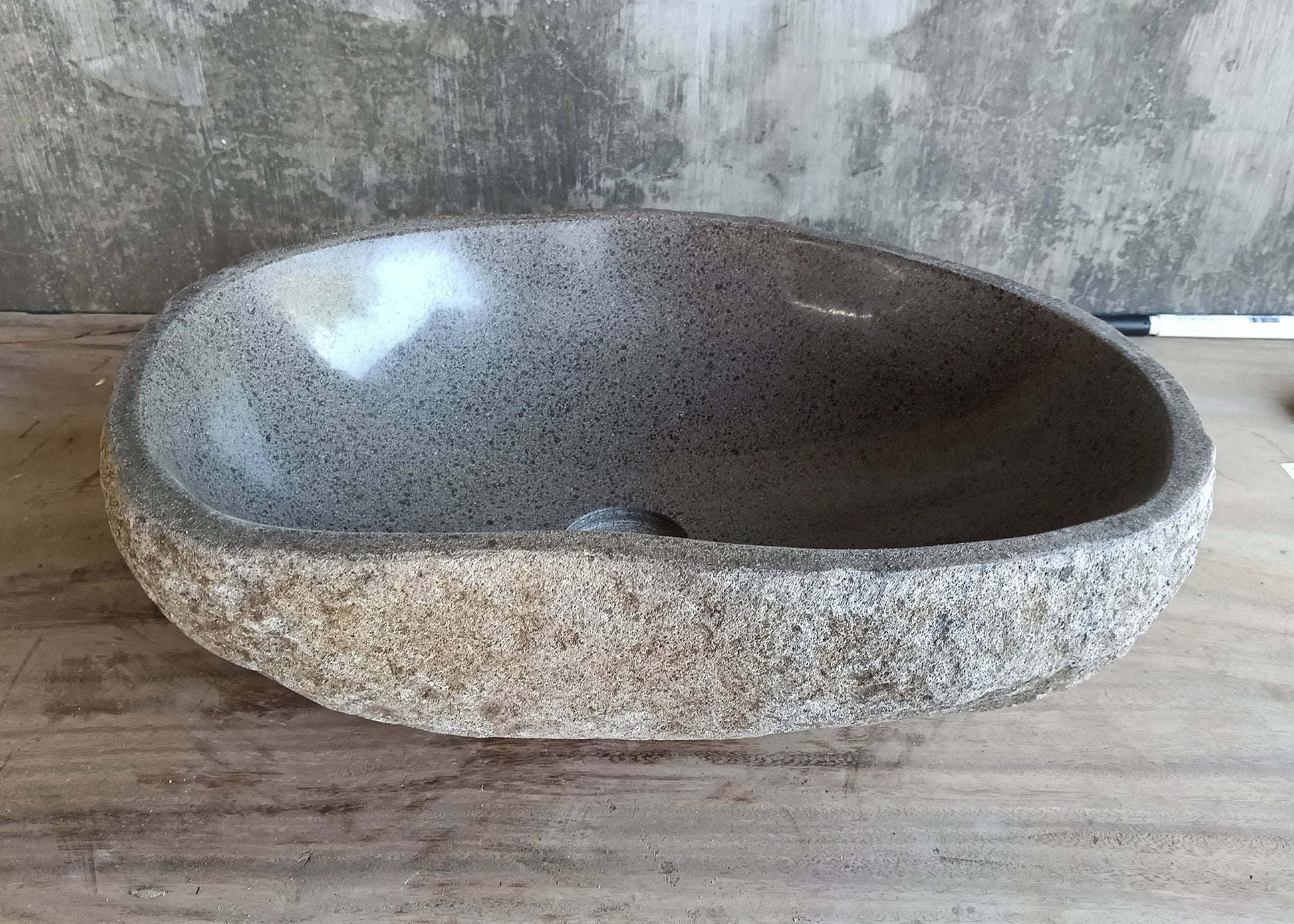 Back view of gray stone sink showing natural rough exterior and organic contours  
