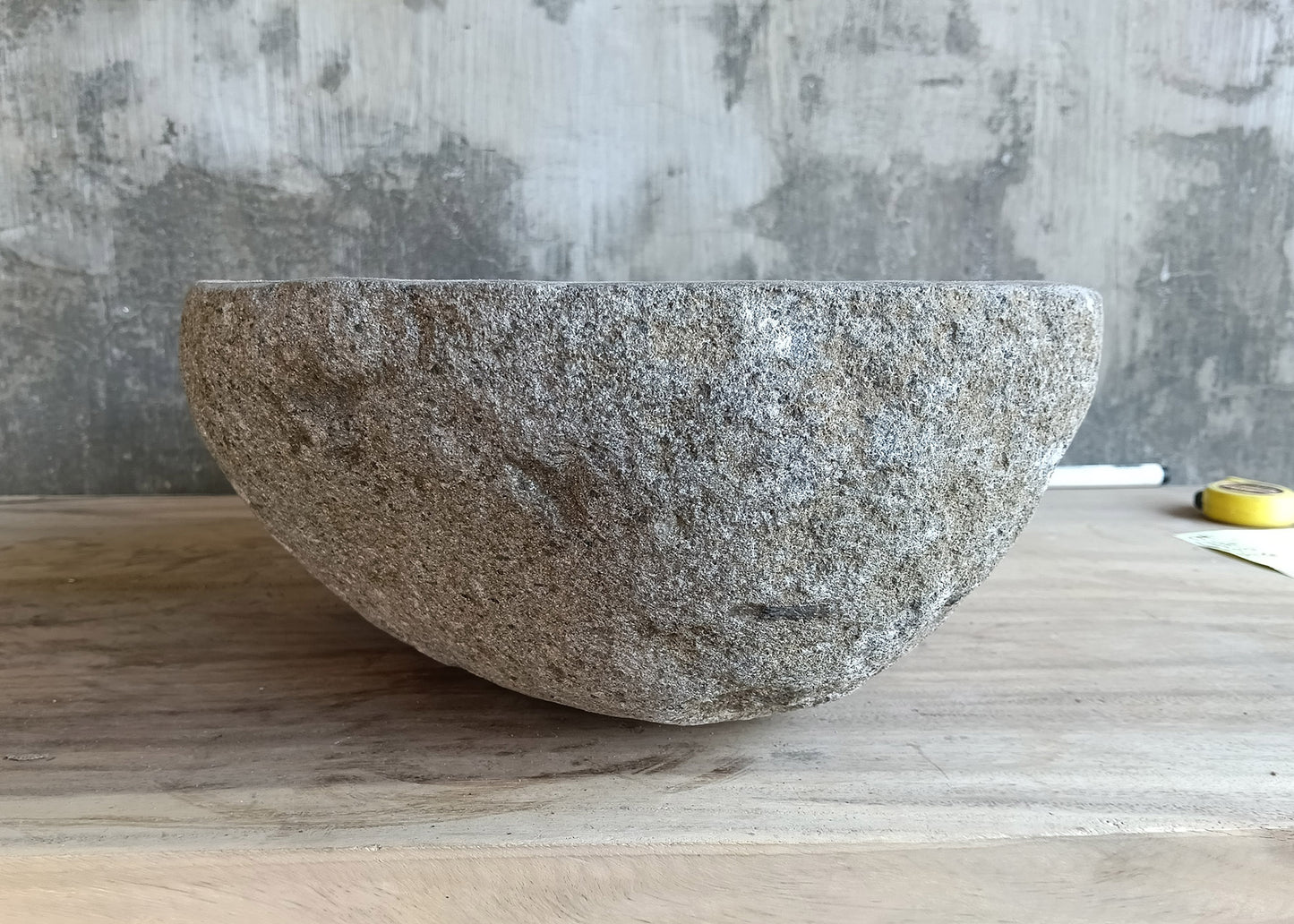 Left side angle of river stone sink with asymmetrical top and carved gray bowl  
