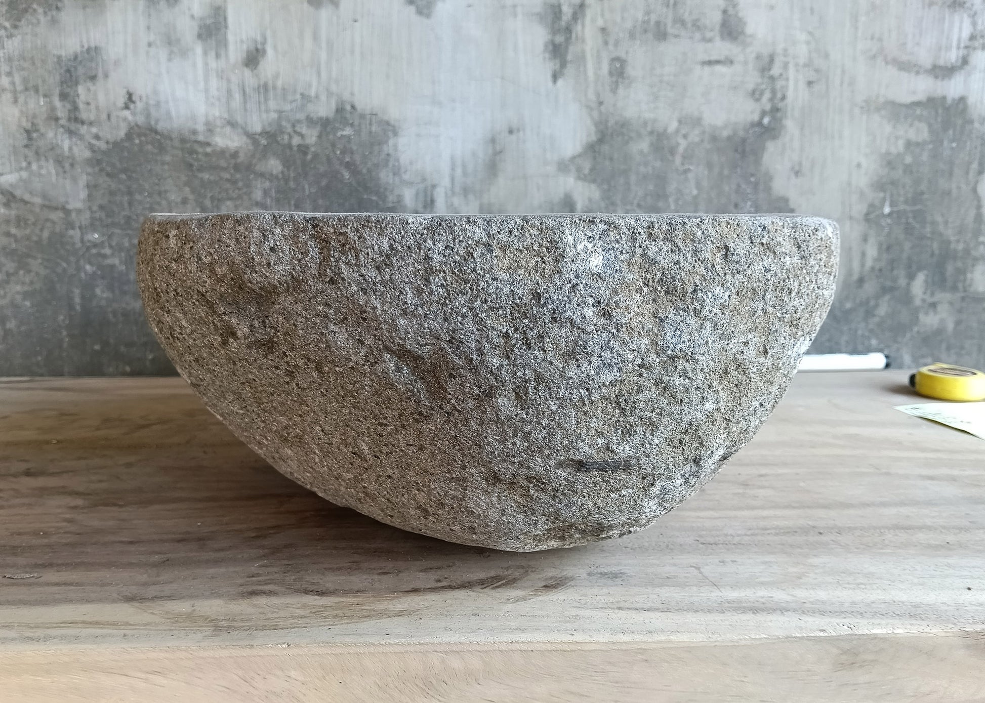 Left side angle of river stone sink with asymmetrical top and carved gray bowl  
