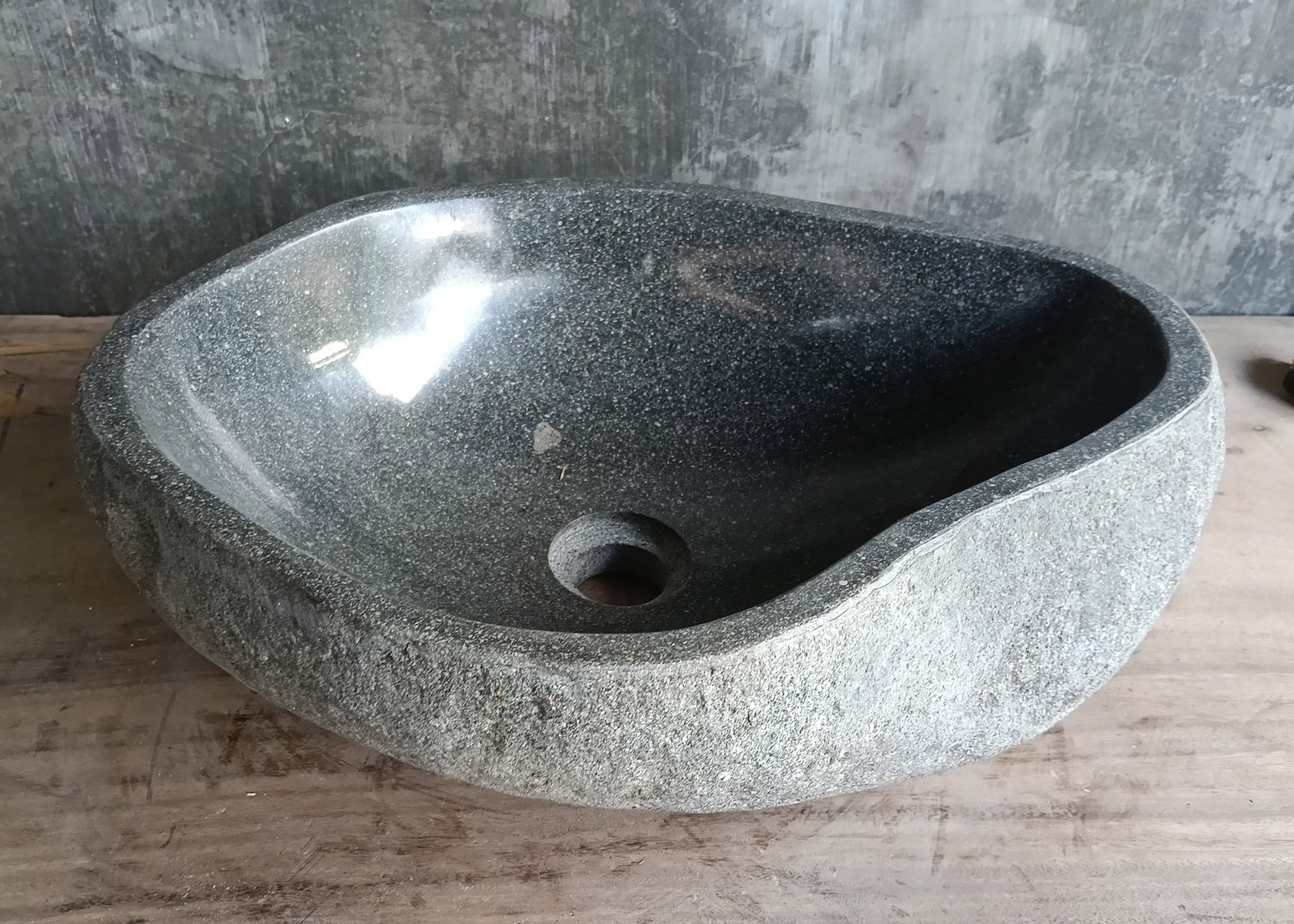 Back view of organic-shaped stone sink with gray surface and natural texture  
