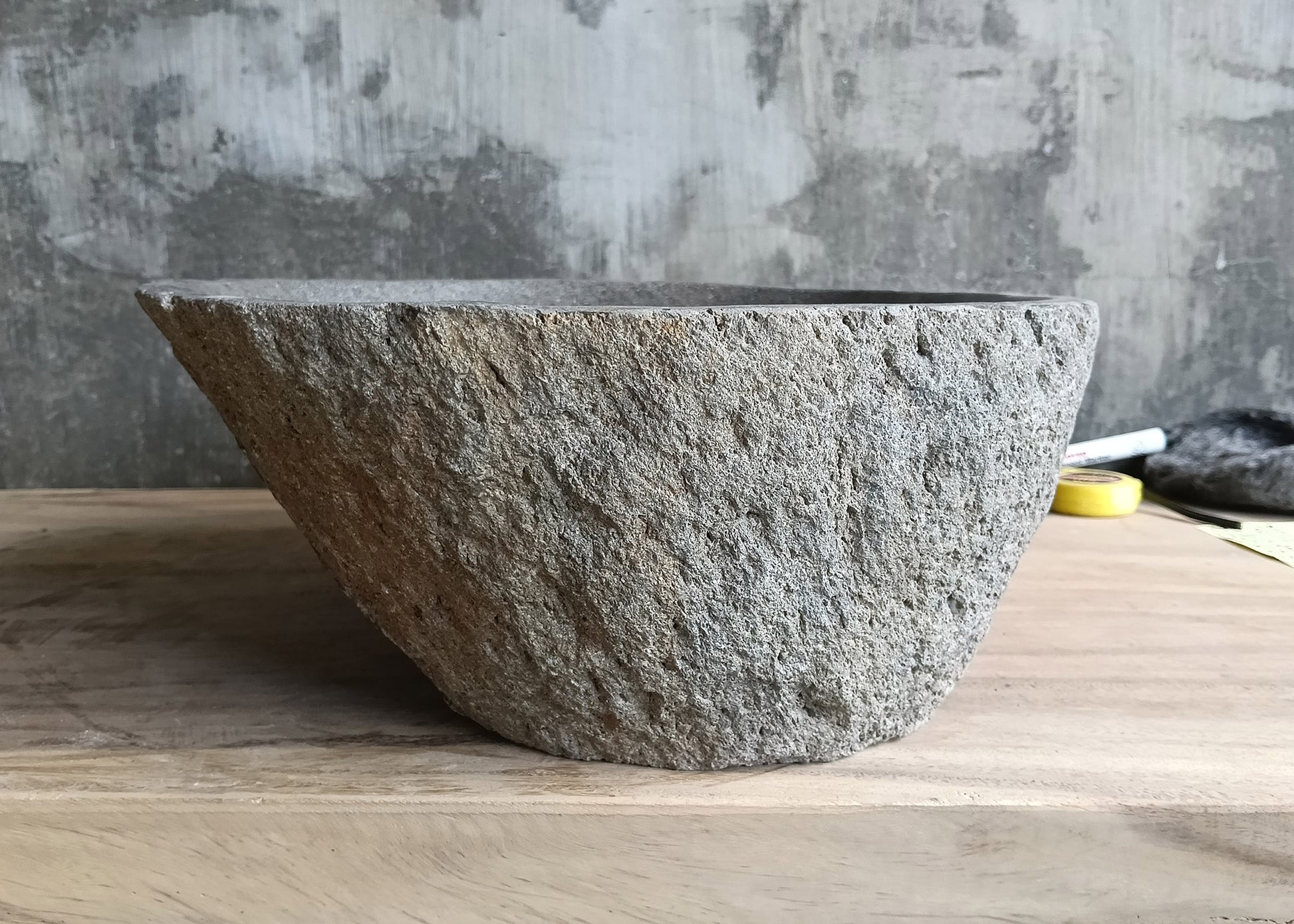 Left side of boat-shaped gray stone sink with rounded oval form  
