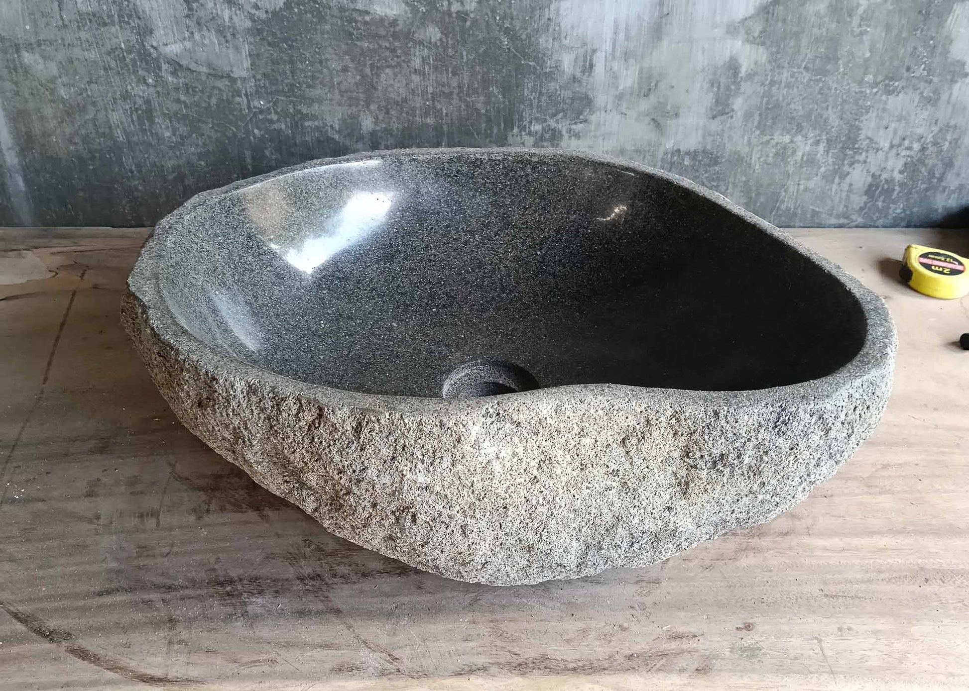 Back of teardrop river stone sink with consistent gray tone and raw stone finish  
