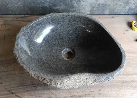 Top view of gray teardrop-shaped river stone sink with smooth porous interior  
