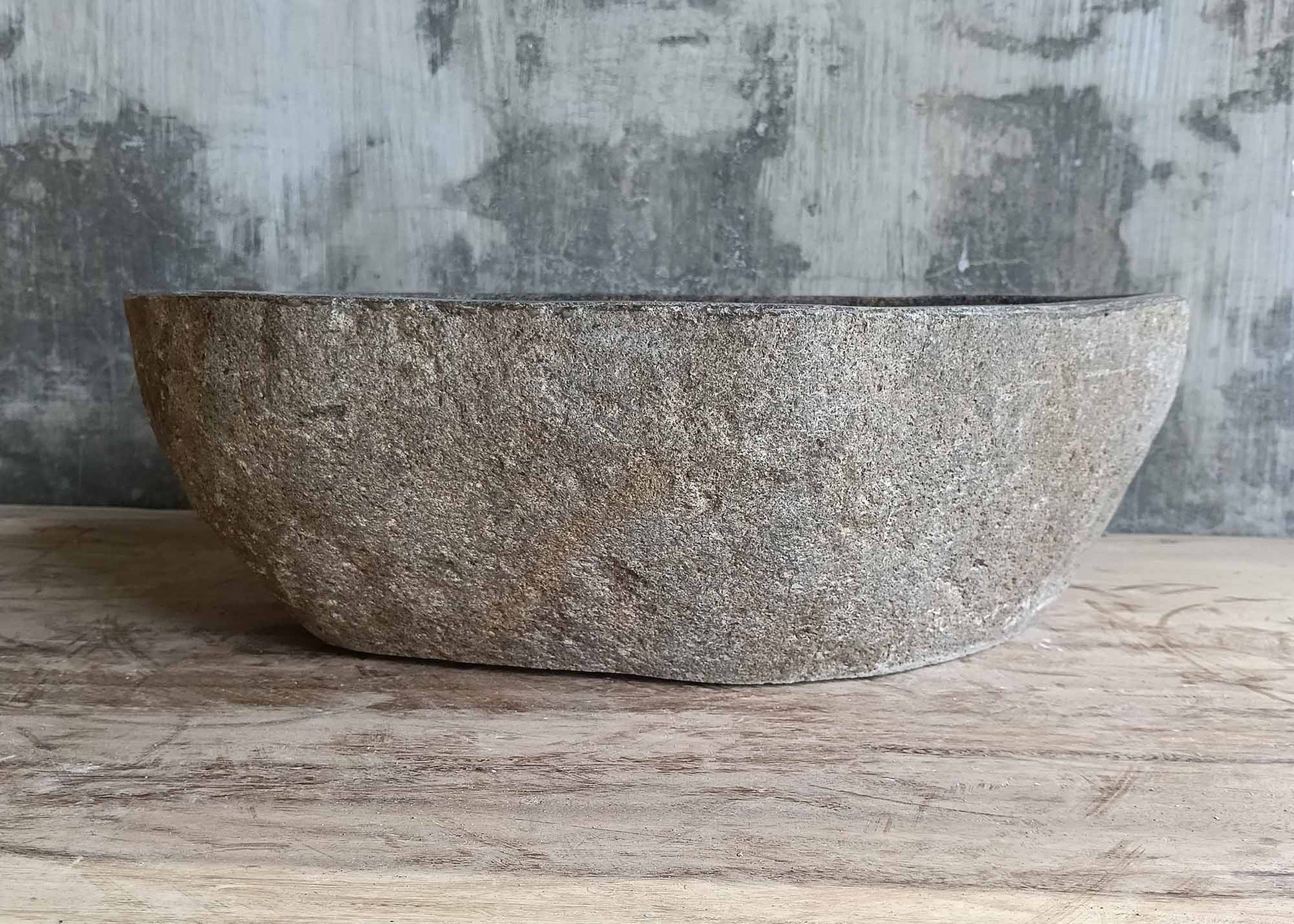 Back of natural gray-brown stone sink with handcrafted rough exterior  
