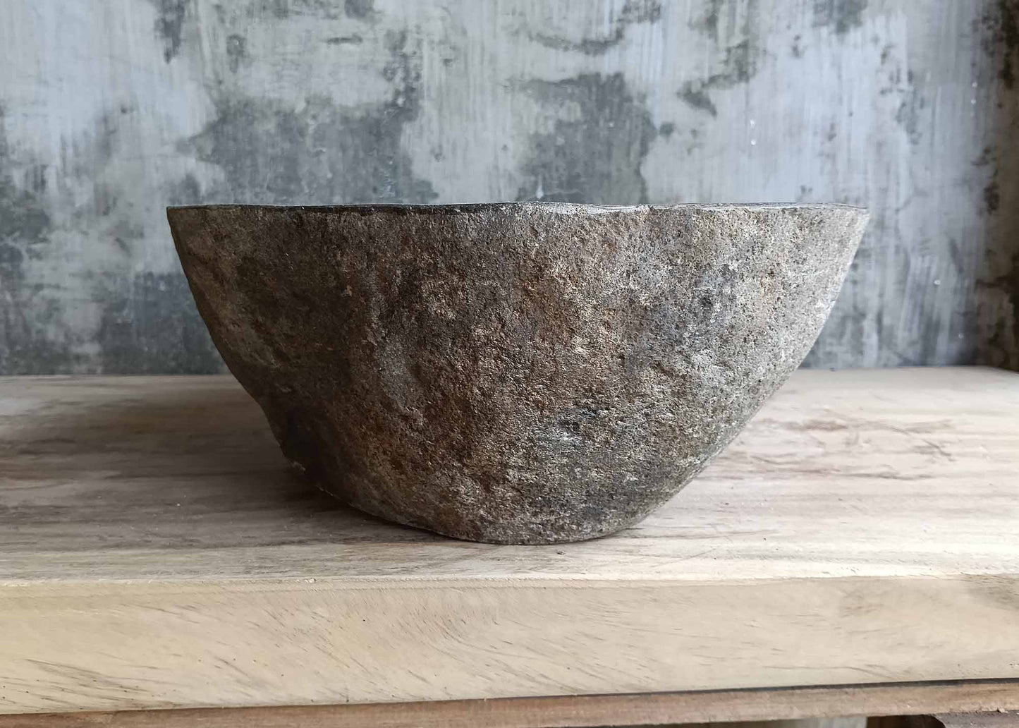 Right view of river stone sink with warm earthy tones and boat-like side curve  
