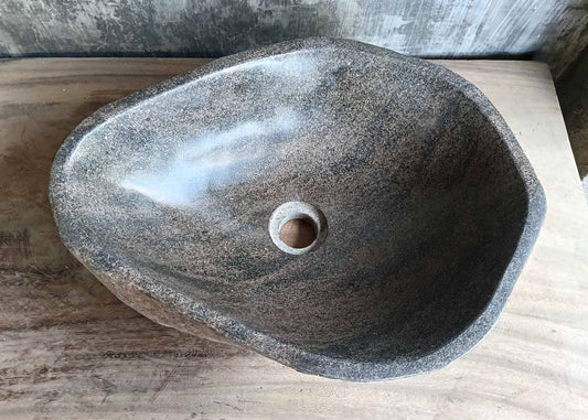 Top view of handcrafted irregular river stone sink with warm gray polished interior  

