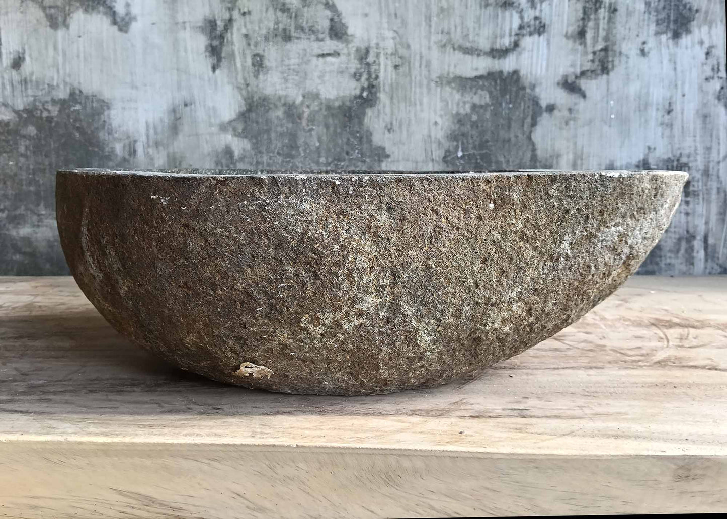 Back side of handcrafted stone sink with rugged outer surface and organic shape  
