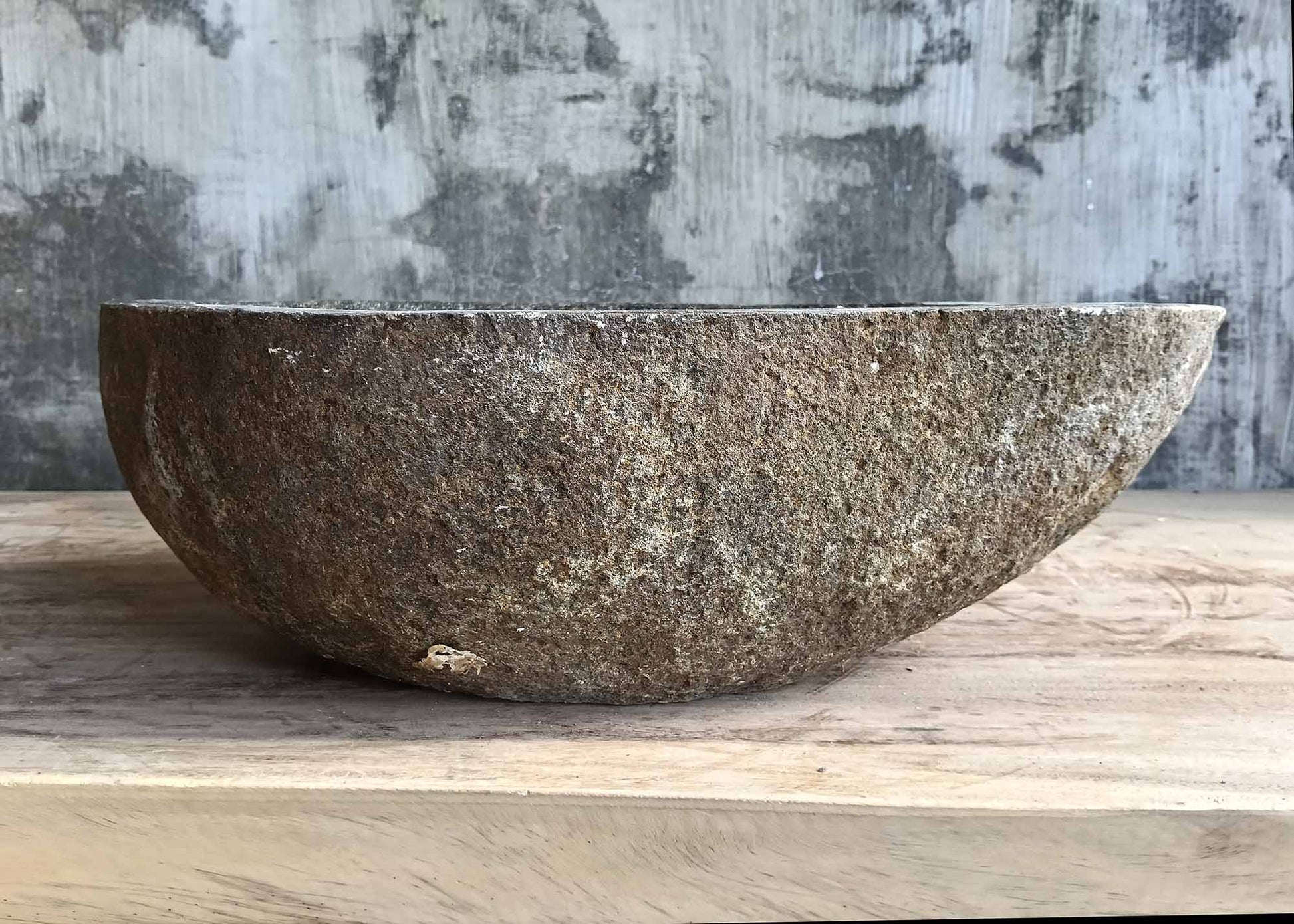 Back side of handcrafted stone sink with rugged outer surface and organic shape  
