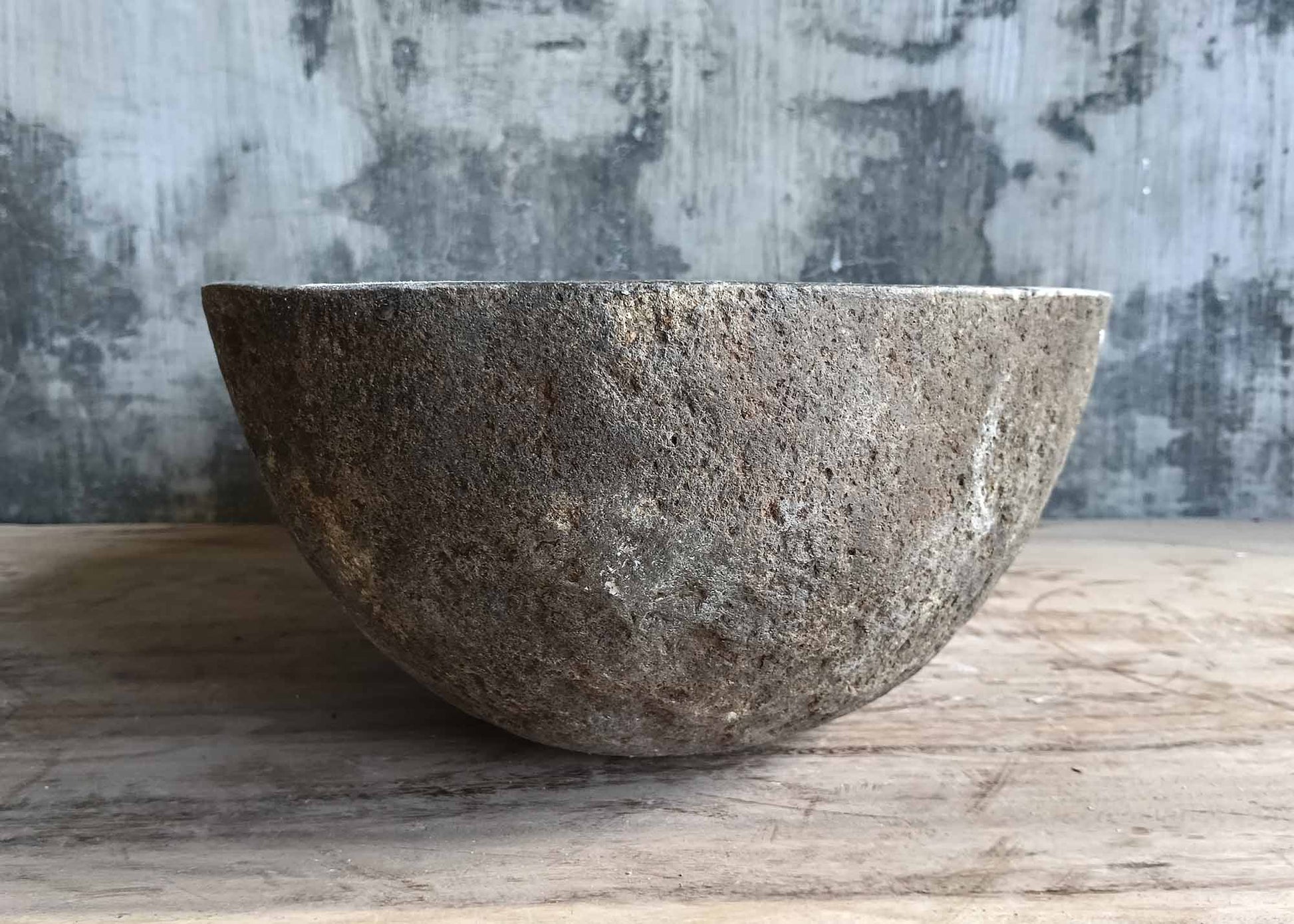 Right side of rustic handcrafted basin with smooth interior and raw brown stone finish  
