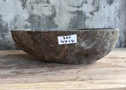 Front of natural river rock sink with boat-shaped contour and brown textured surface  
