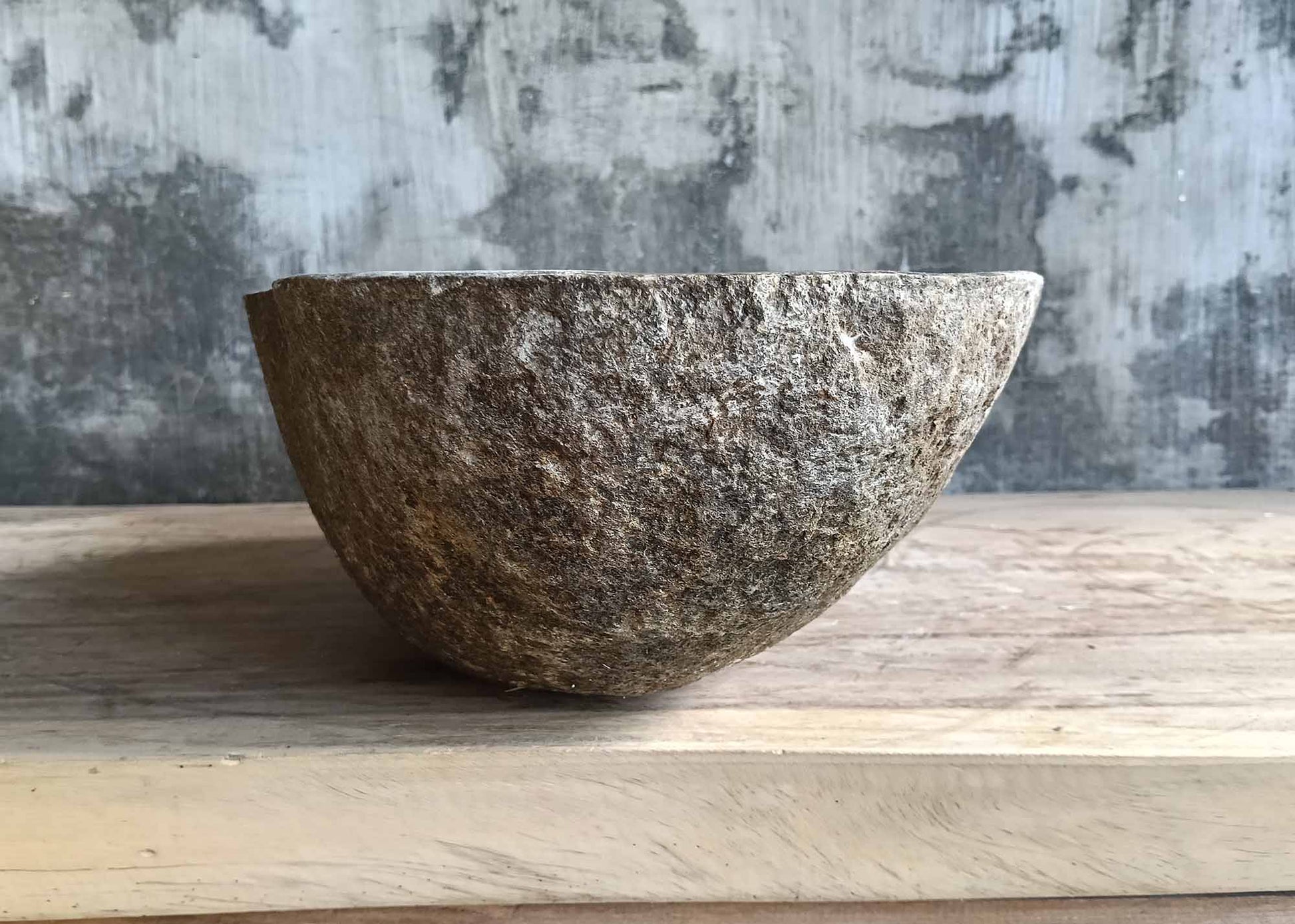 Left view of oval river stone sink with asymmetrical polished bowl  

