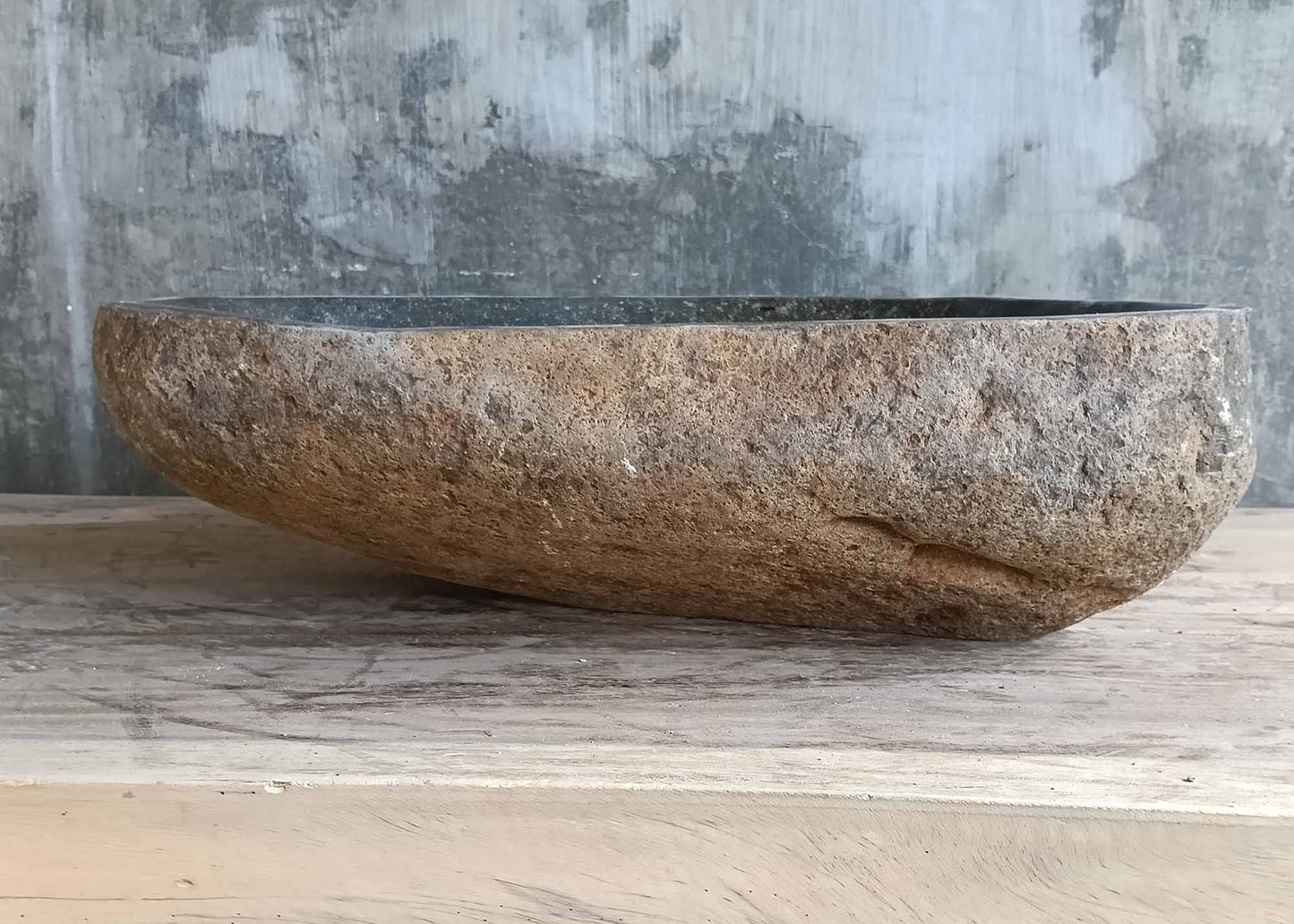Back view of handcrafted river sink showing rugged natural stone surface and contour  
