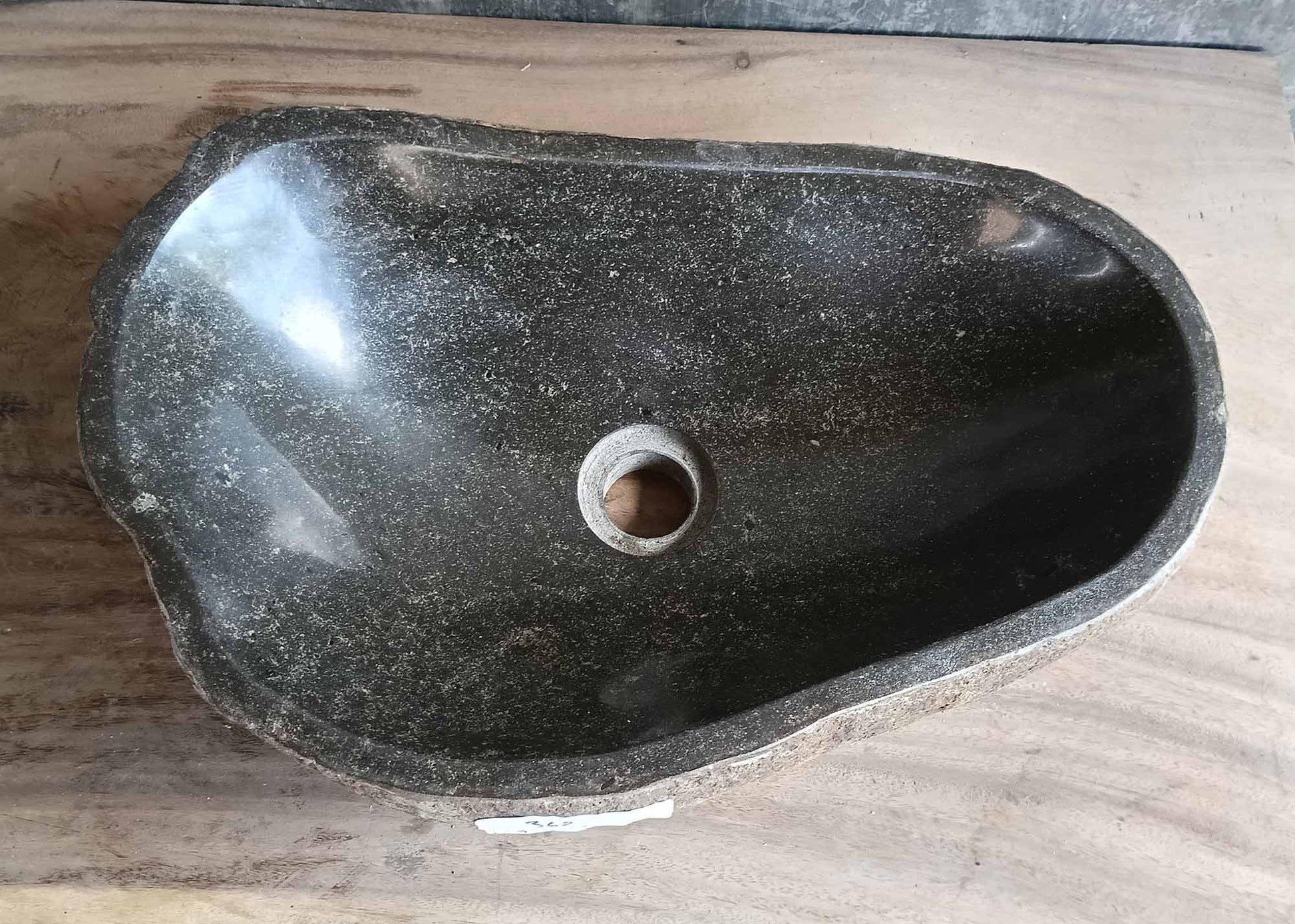 Top view of dark gray handcrafted stone sink with irregular oval shape and polished interior  
