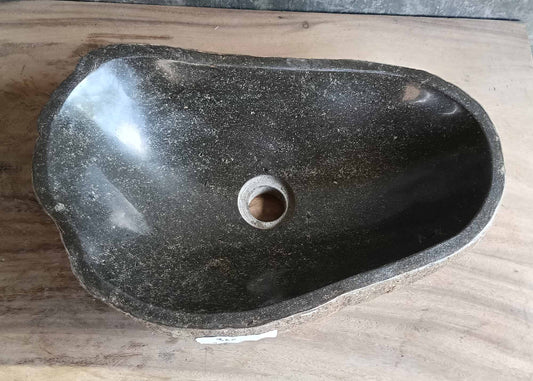 Top view of dark gray handcrafted stone sink with irregular oval shape and polished interior  
