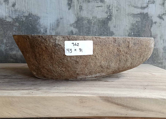 Front of river stone basin with boat-like curve and warm brown raw stone texture  
