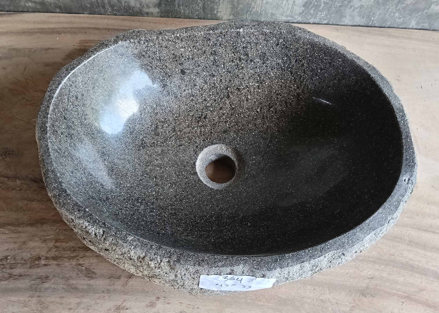 Top view of handcrafted gray river stone sink with soft oval shape and polished interior  
