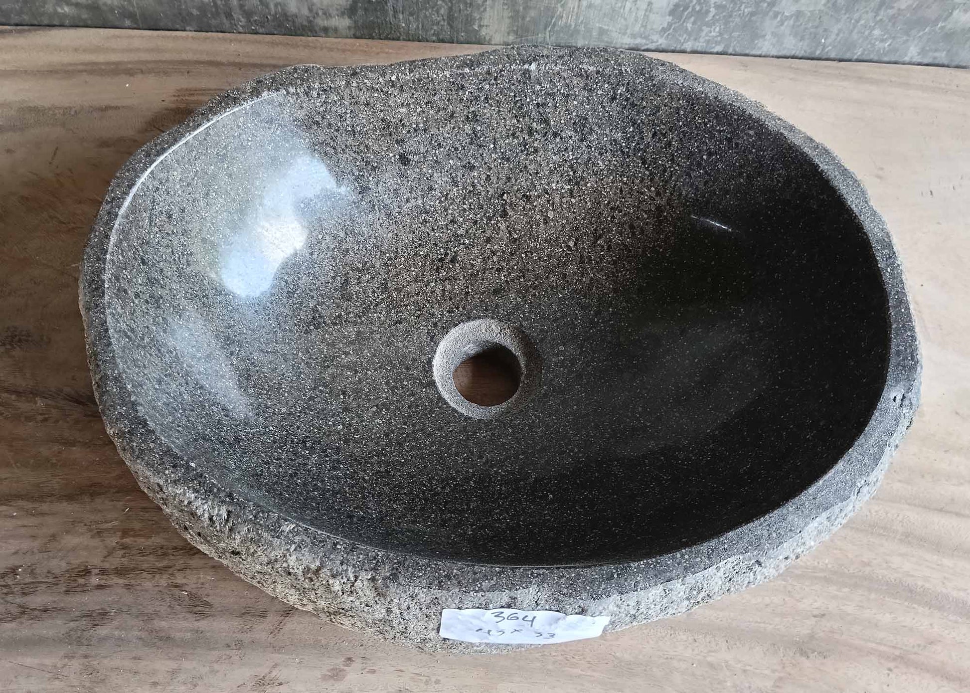 Top view of handcrafted gray river stone sink with soft oval shape and polished interior  
