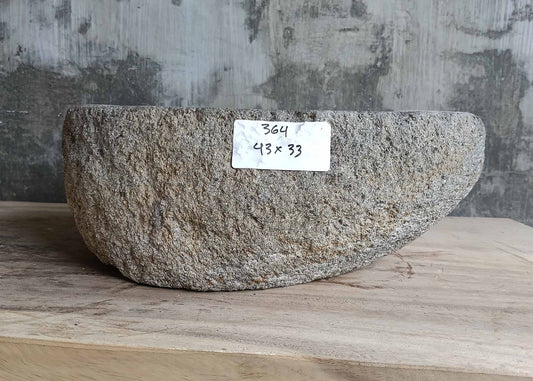 Front of natural stone sink with raw textured exterior and boat-like silhouette  
