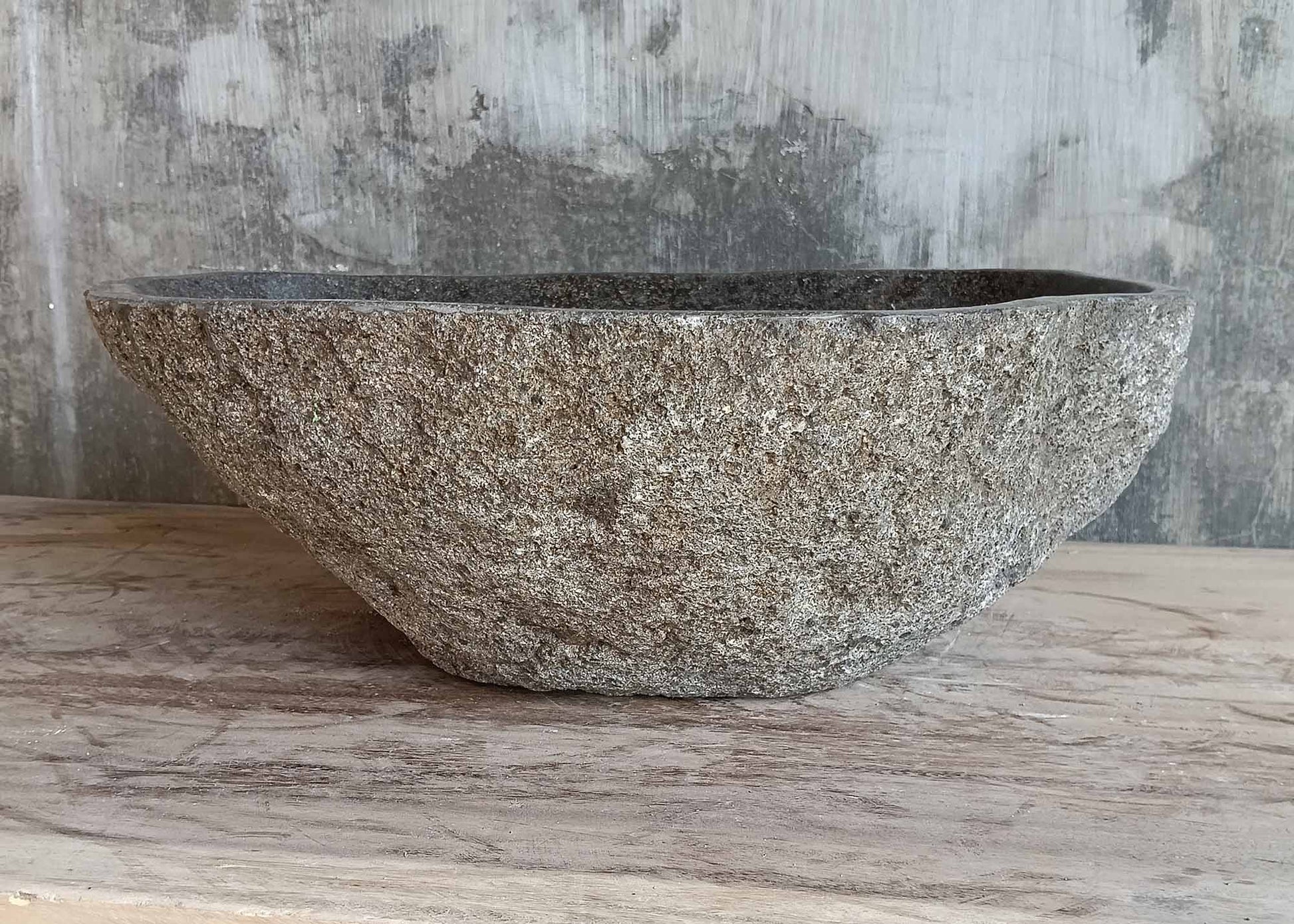 Top view of hand-polished grey stone sink with drain hole
