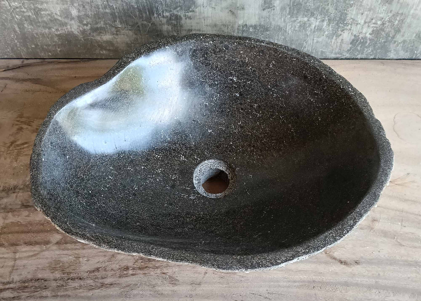 Side view of handcrafted grey river stone sink with rough natural texture
