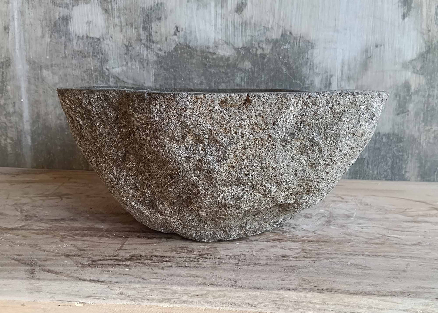 Angled back side of rustic river stone sink with raw exterior

