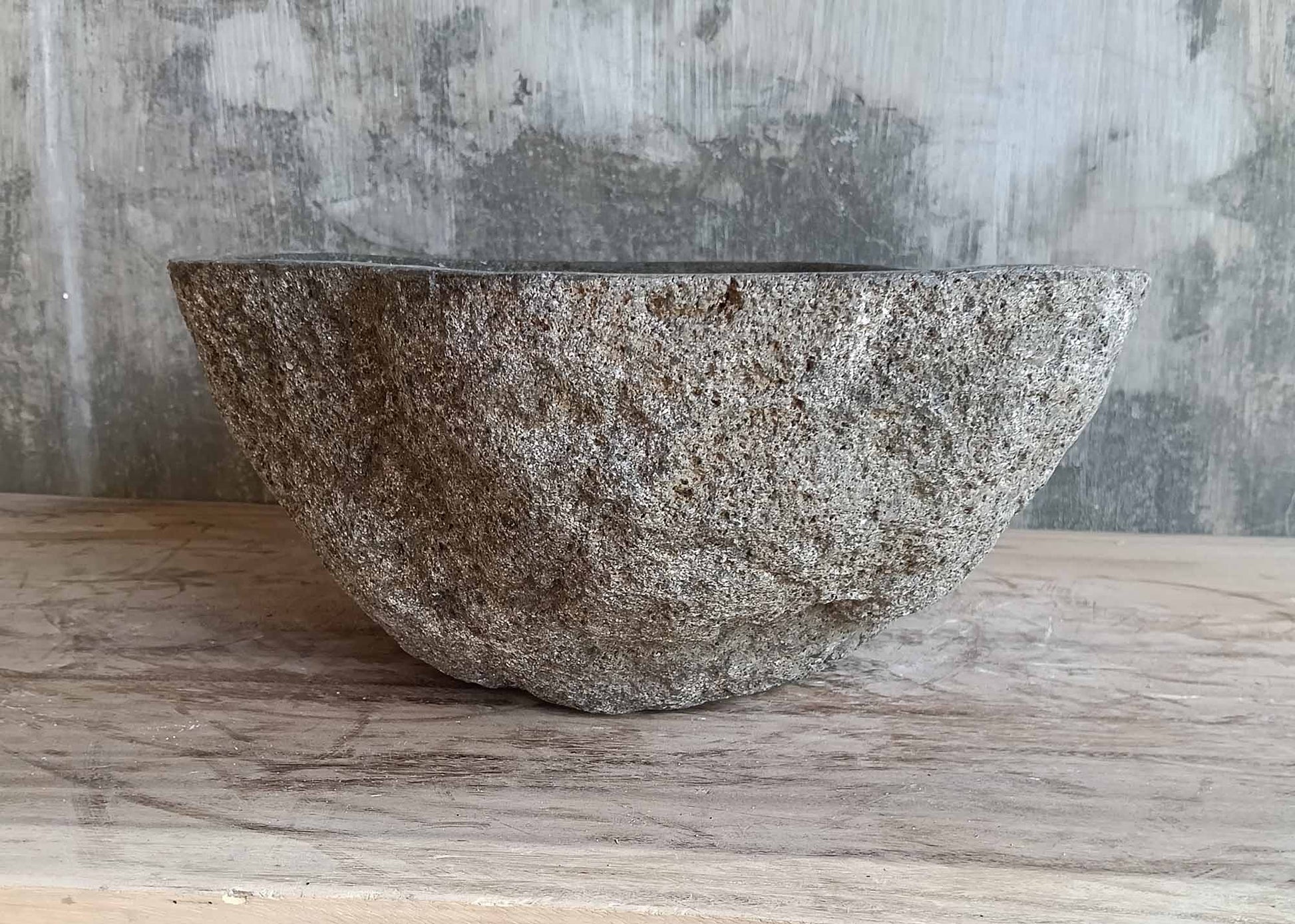 Angled back side of rustic river stone sink with raw exterior
