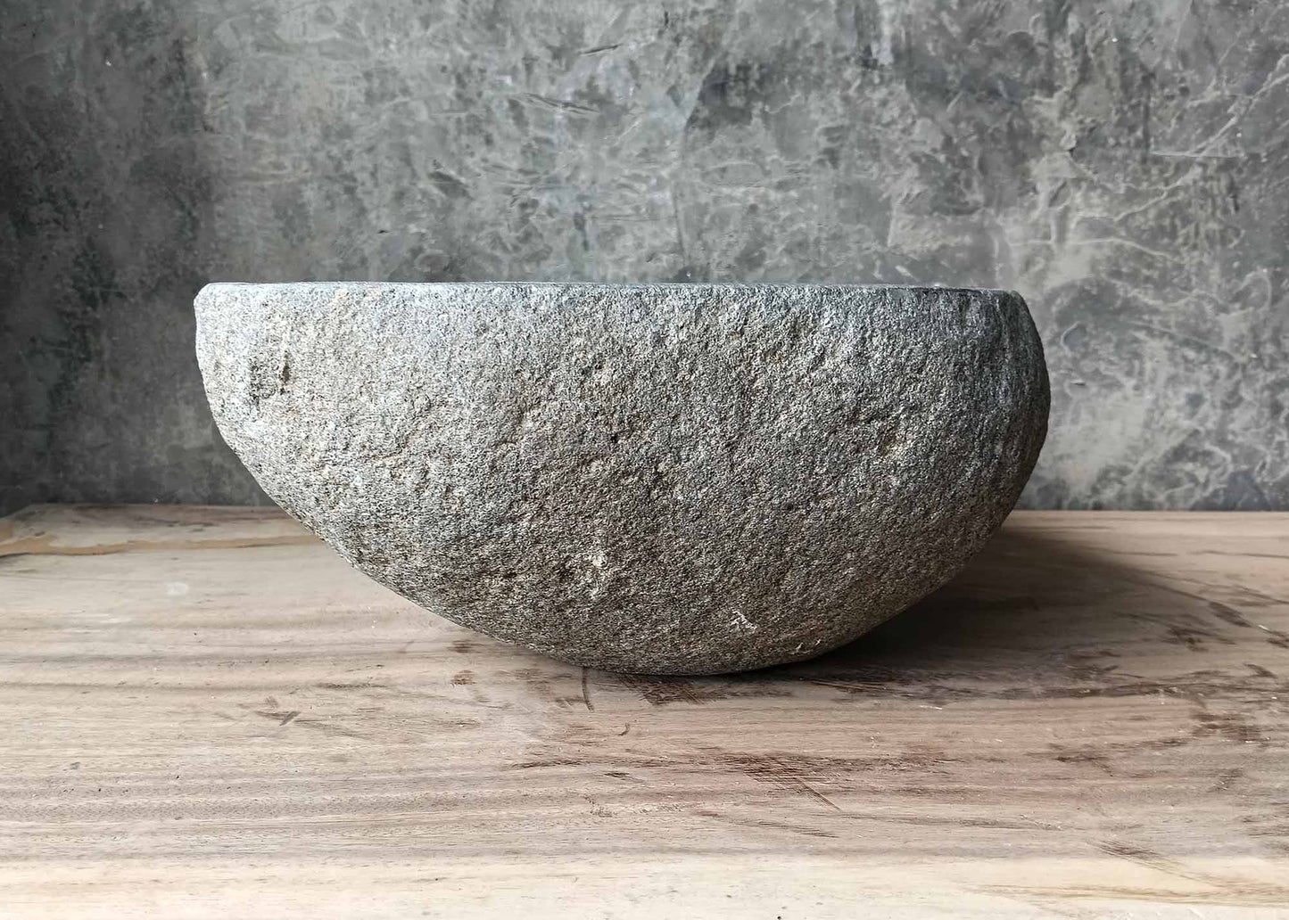 Right side of oval river stone sink with rough handcrafted exterior

