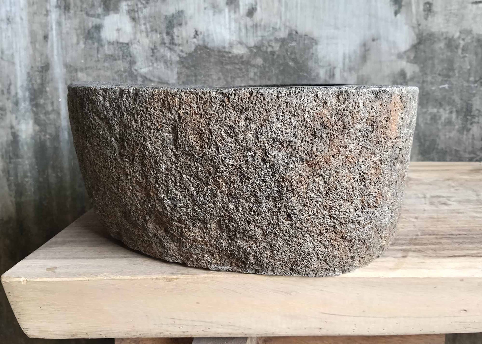 Right-side view of asymmetrical stone sink with coarse pumice-like exterior

