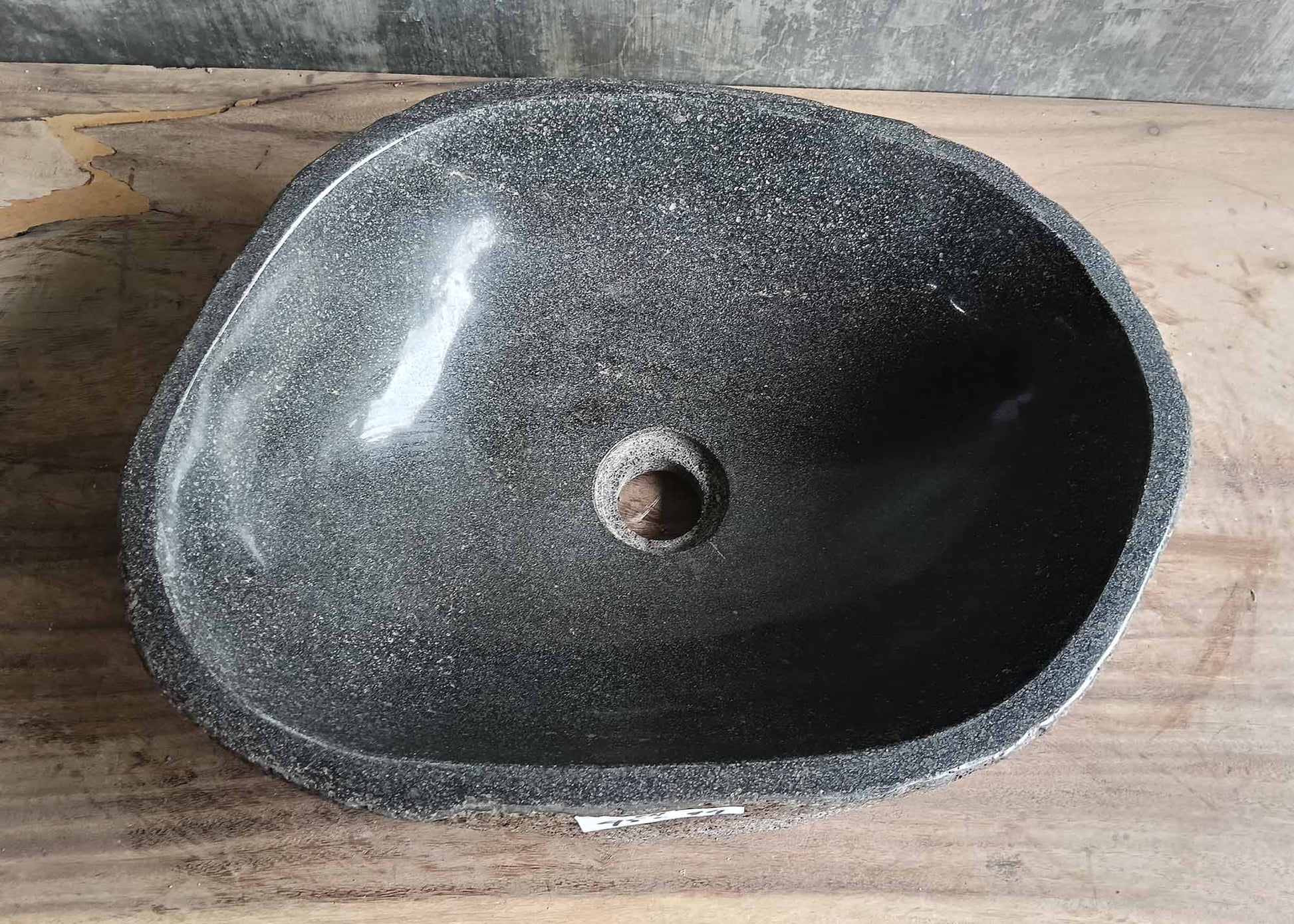 Top-down view of handcrafted river stone sink with deep polished basin and organic dark surface

