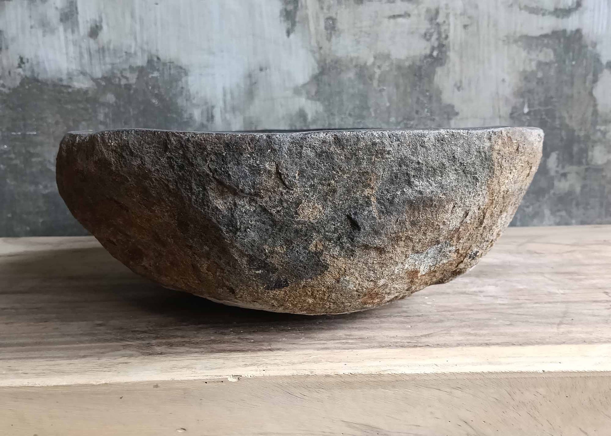 Right edge of stone vessel sink in warm brown and charcoal hues
