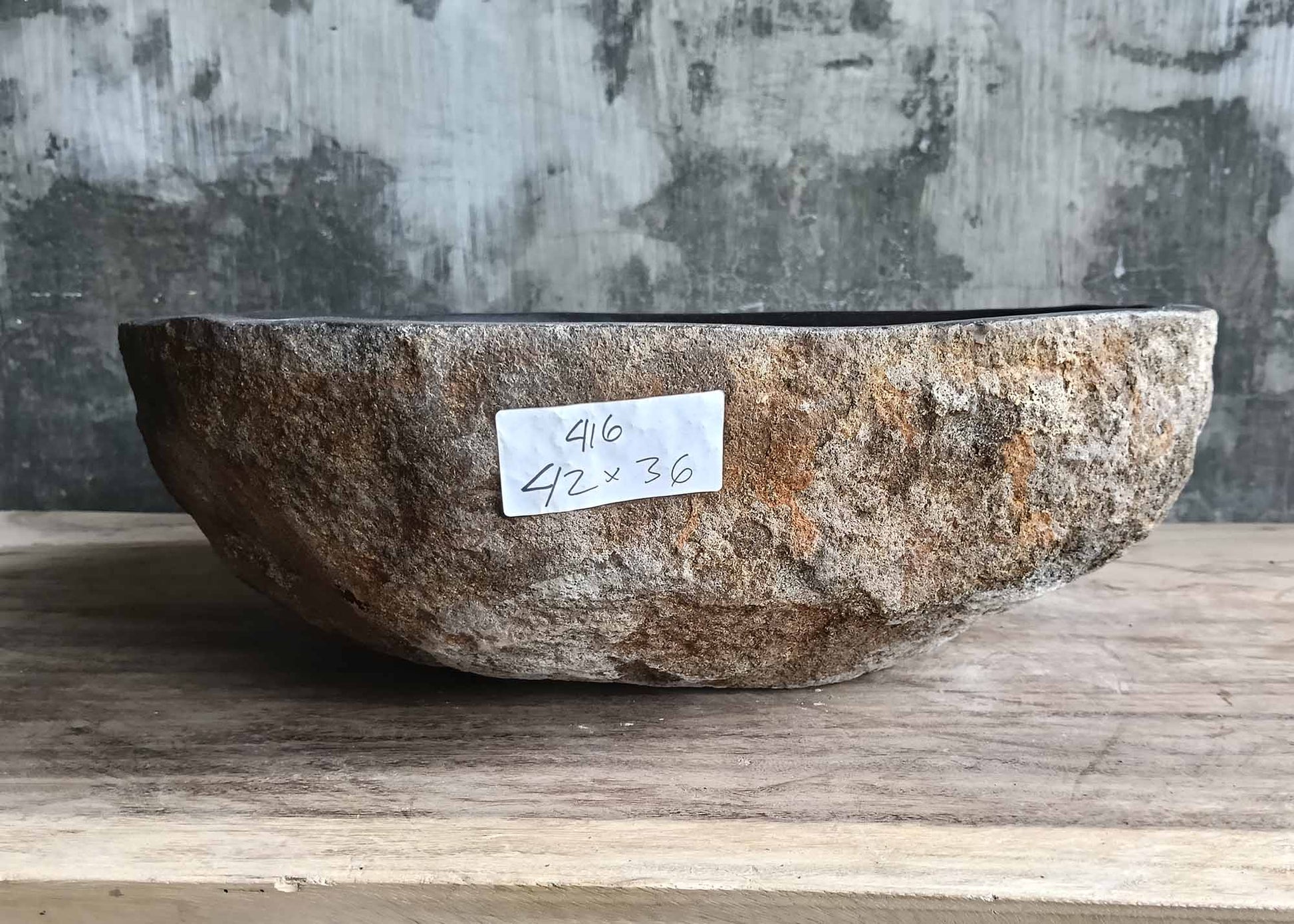 Front of handcrafted stone sink with rich rusty and beige tones
