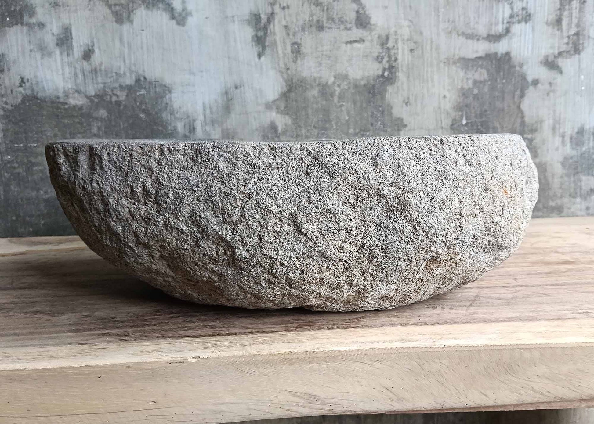 Back side of a handcrafted stone basin showing rough stone surface
