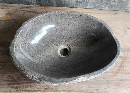 Top view of a handcrafted river stone sink with smooth grey polished interior and natural edges
