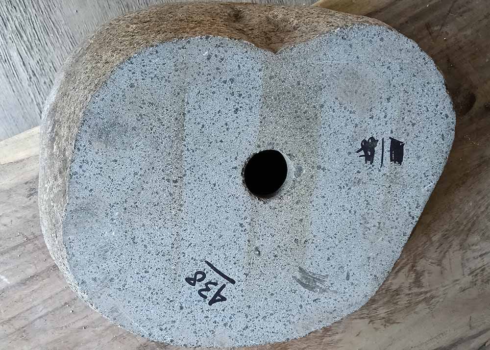 Underside of river stone sink showing drain hole and unpolished base
