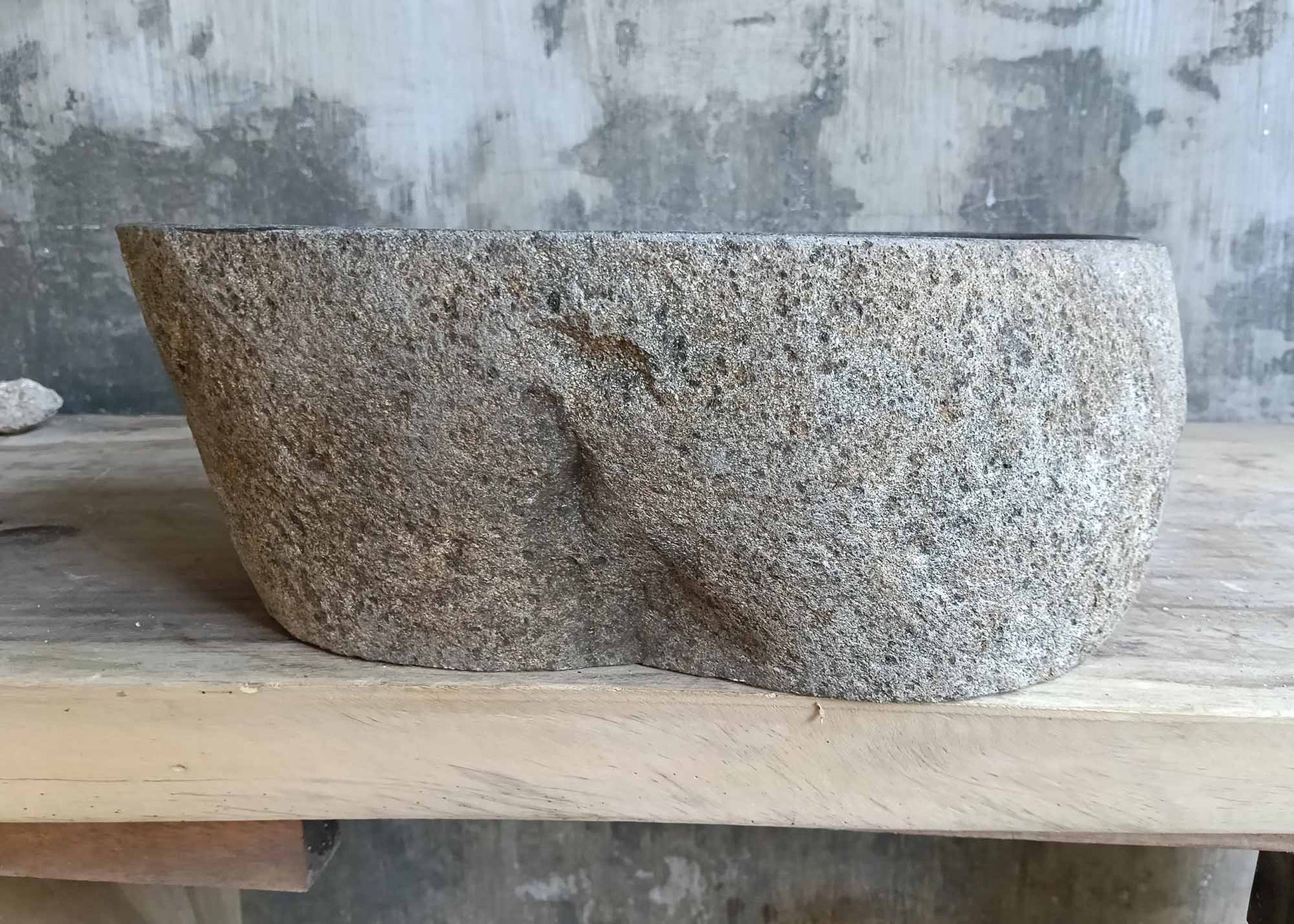 Backside of oval river stone sink with textured natural stone finish
