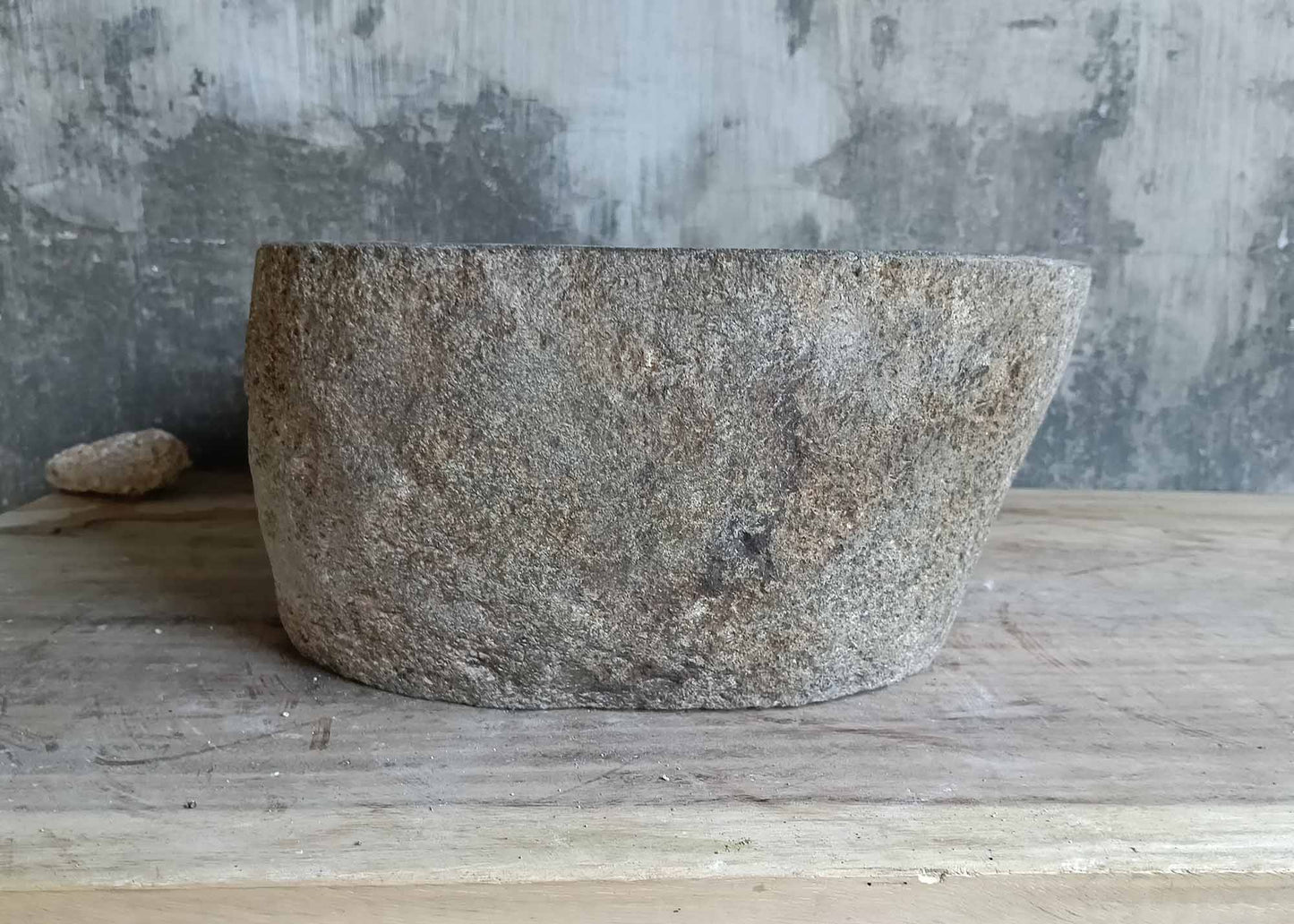 Left angle of gray oval river stone sink highlighting curved silhouette
