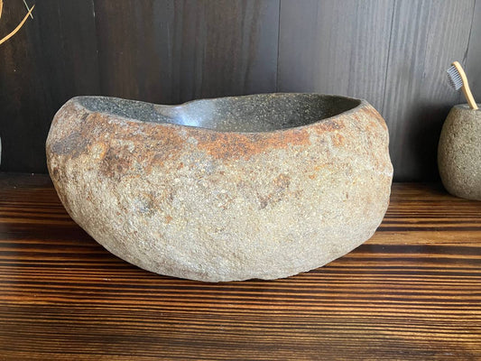 Front angled view of light-gray river stone sink with warm mineral accents