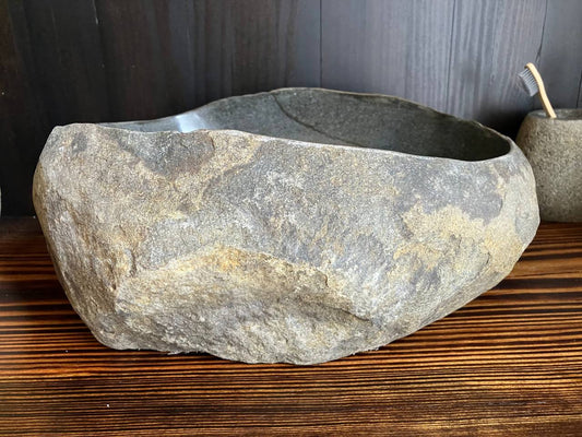 Front view of charcoal-black river stone sink with rust-orange mineral bands