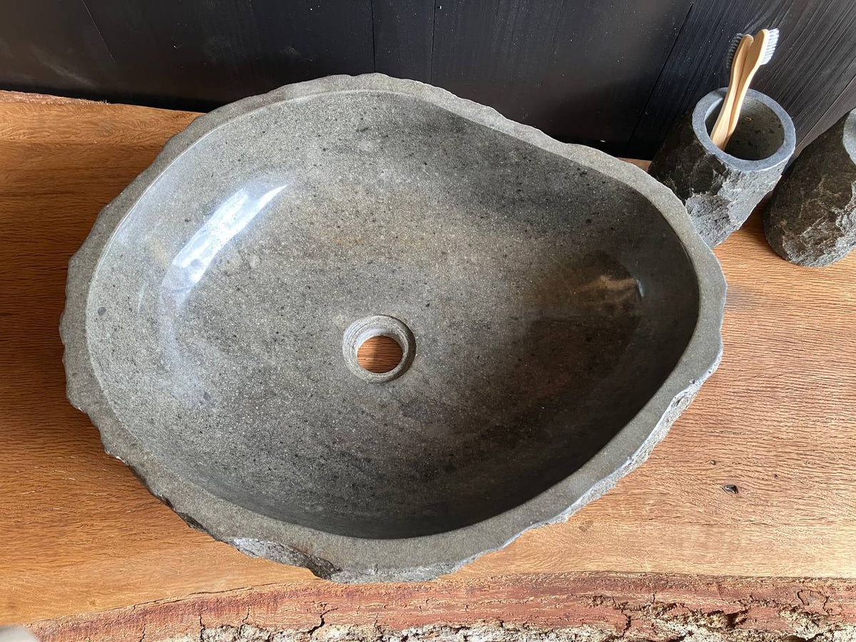 Gray andesite stone vessel sink ANS-001 with a rough chiseled exterior on a wood bathroom countertop