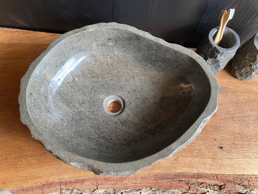 Gray andesite stone vessel sink ANS-001 with a rough chiseled exterior on a wood bathroom countertop