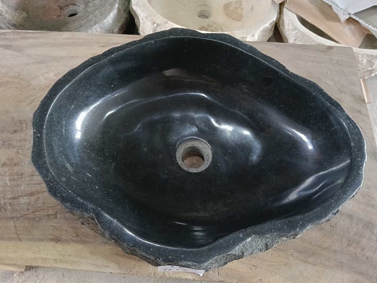 Top view of A92-5241 black andesite stone sink with polished interior and rough chiseled exterior, elongated organic oval shape.
