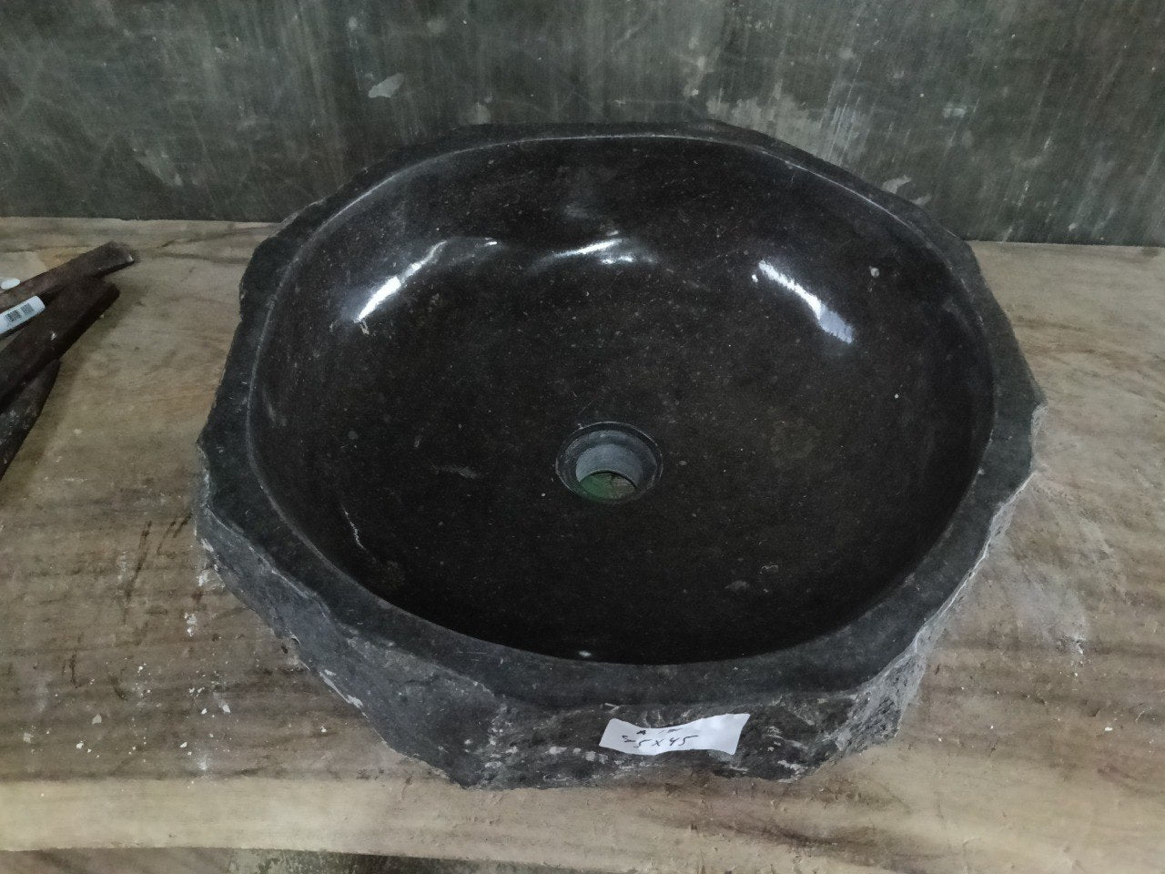Top view of A136-4545 black andesite stone sink with polished interior and rough chiseled exterior, round shape.
