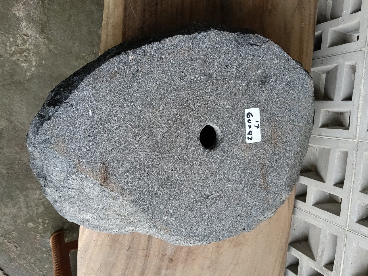 Bottom view of oval andesite stone sink with drain hole

