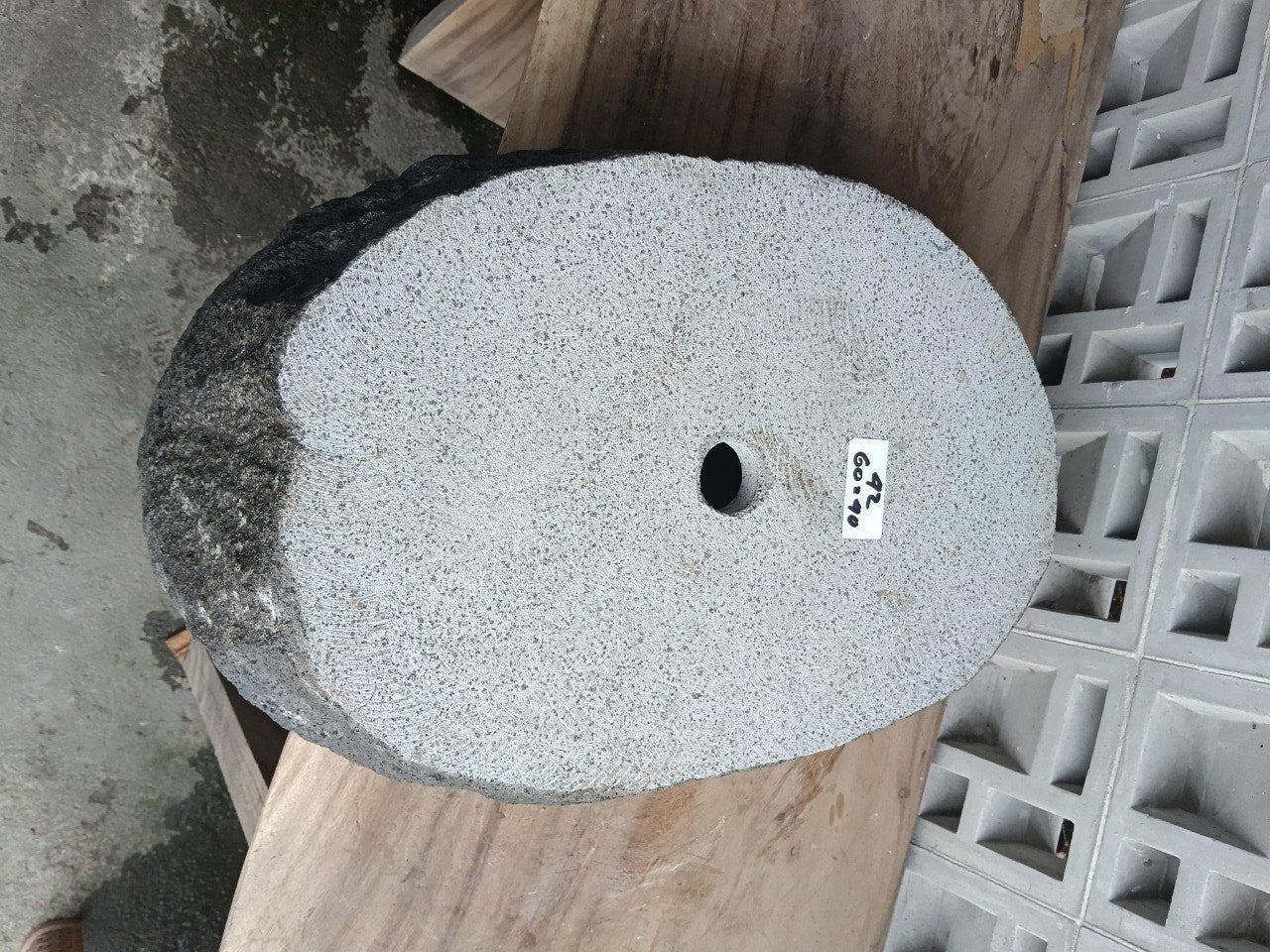 Bottom view of elongated oval andesite stone sink with drain hole

