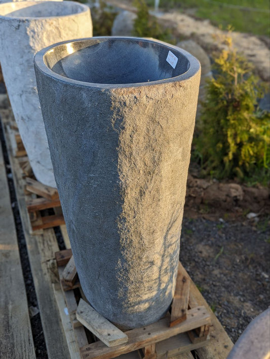 Front view of natural river stone pedestal sink with textured surface
