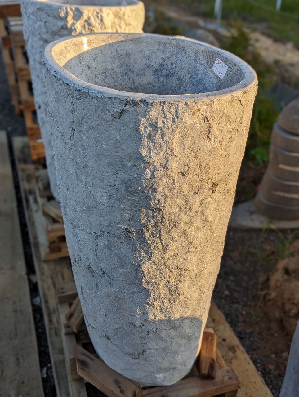 Front view of gray marble pedestal sink with rough texture
