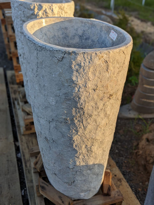 Front view of gray marble pedestal sink with rough texture
