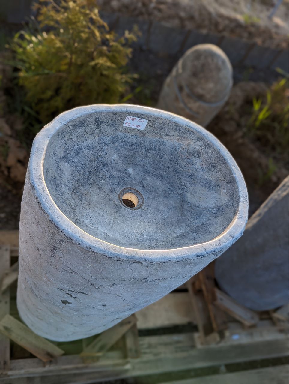 Close-up of rough stone texture on gray marble pedestal sink
