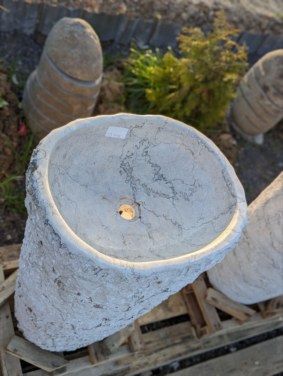 Close-up of rough stone texture on white marble pedestal sink
