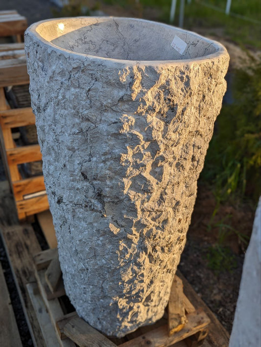 Front view of white marble pedestal sink with rough finish
